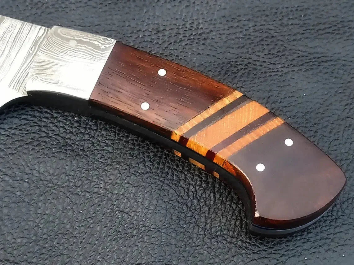 Handmade Damascus steel knife with wooden handle on black surface